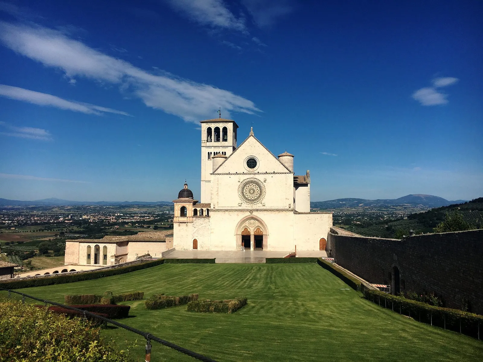 The basilica of San Francesco in Assisi with its sloping lawn and the valley