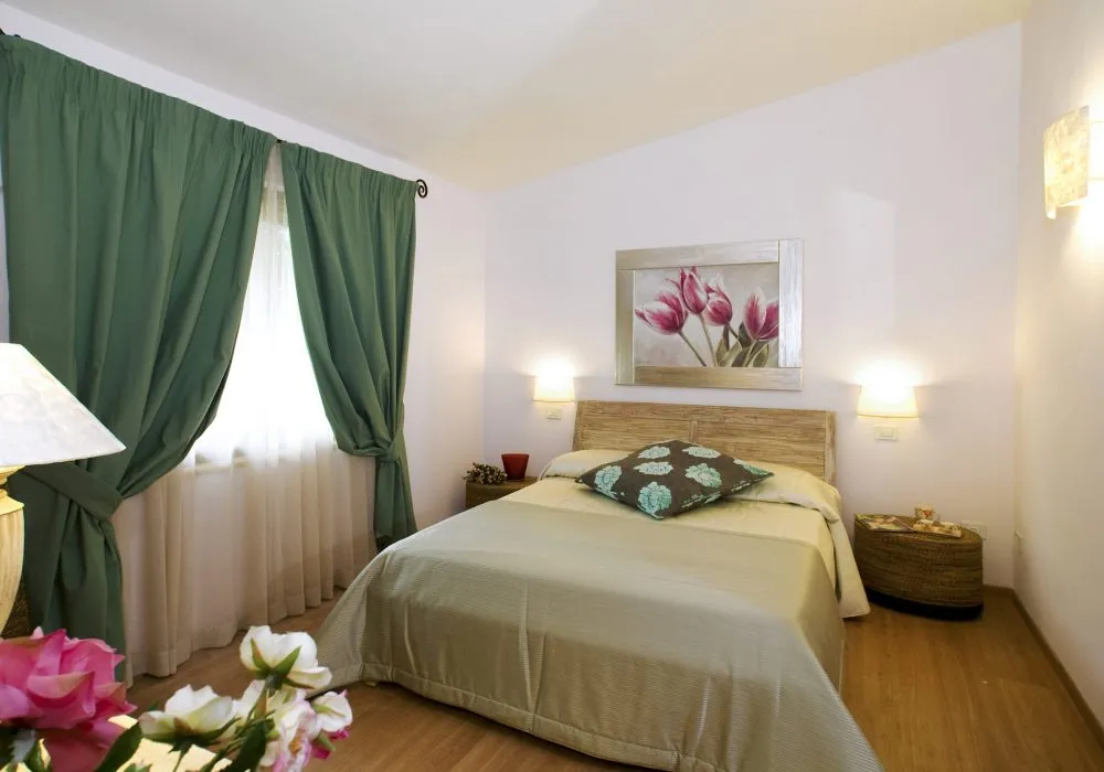 Room with green curtains, a light wood headboard and a pink tulip print