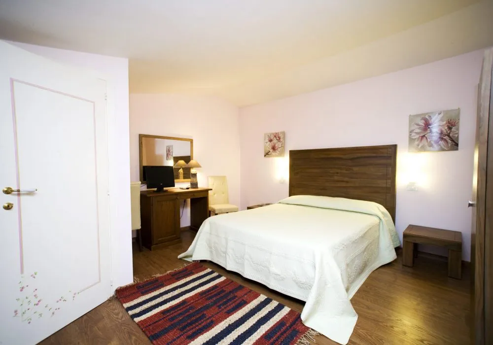 Room with a dark wood headboard, small floral prints and a white door hand-painted with a floral motif
