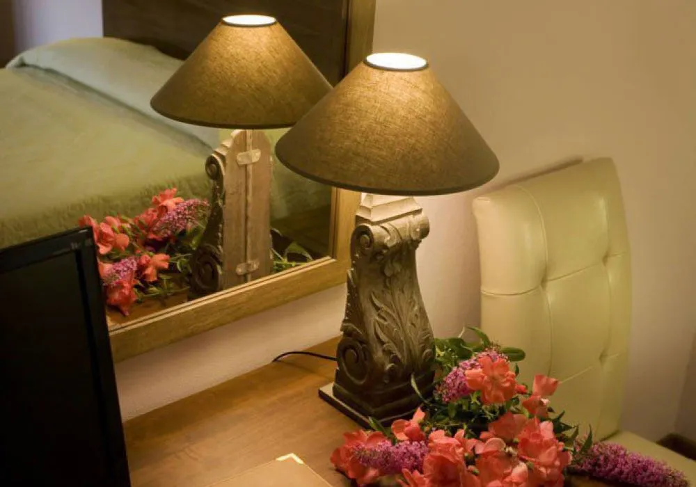 Dettaglio di una lampada da comodino in legno intagliato con un mazzo di fiori recisi