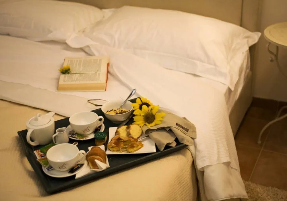 Vassoio della colazione a letto con caffettiera, tazze, cornetto e girasoli
