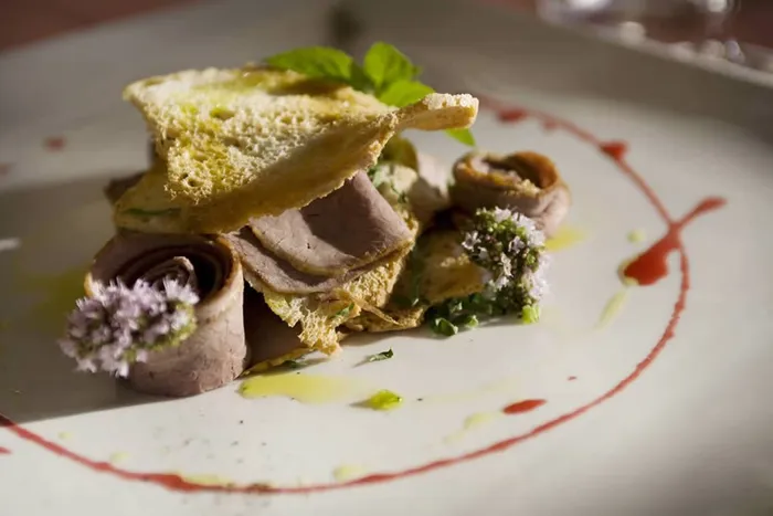 Piatto di roast beef con cialde croccanti, fiori di erba cipollina e salsa rossa