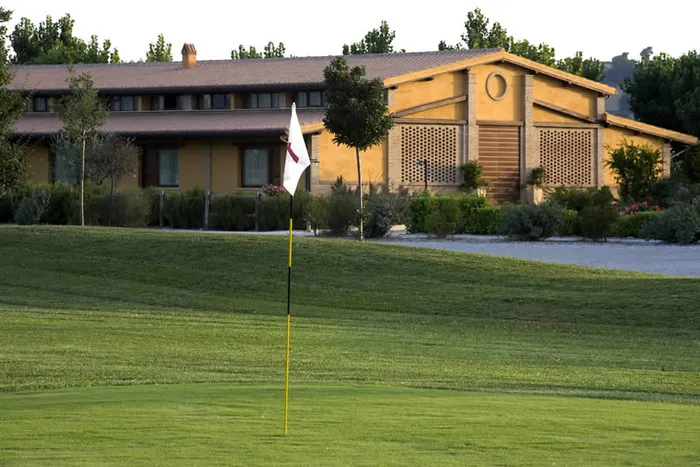 Green del campo da golf con la bandierina, davanti all'edificio giallo ocra