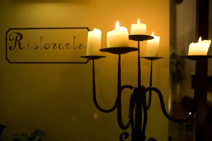 Candelabro in ferro con candele accese davanti alla vetrata incisa Ristorante