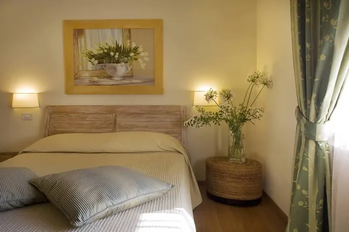 Bed with a pale wooden headboard and sage-green linen, and a white tulip painting