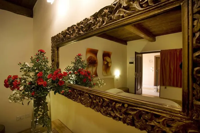 Vaso di rose rosse e bianche davanti a un grande specchio dalla cornice intagliata