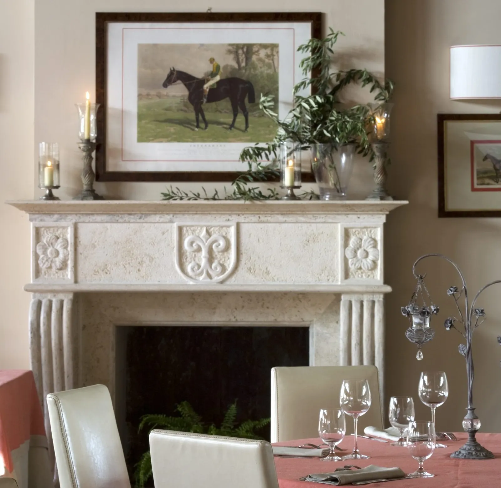 Stone fireplace with a horse print and candles, in front of a laid table