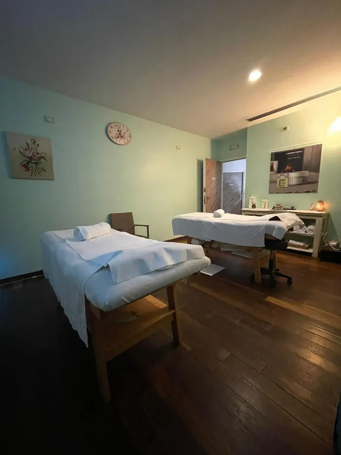 Treatment room with two prepared tables, aqua-green walls and a dark wood floor