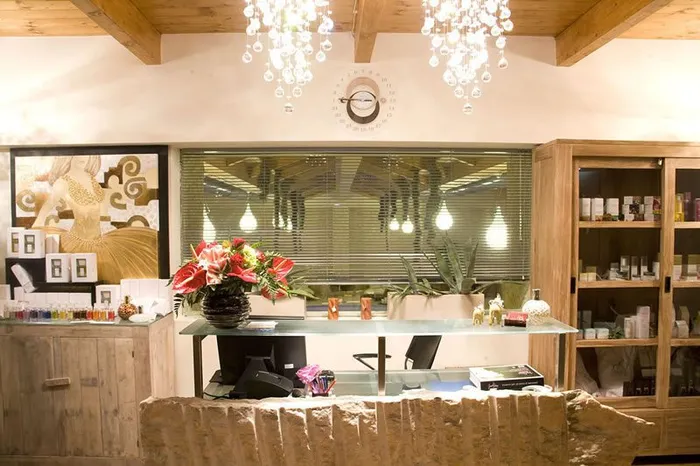 Reception della spa con bancone in pietra, lampadari a gocce e vetrine di prodotti